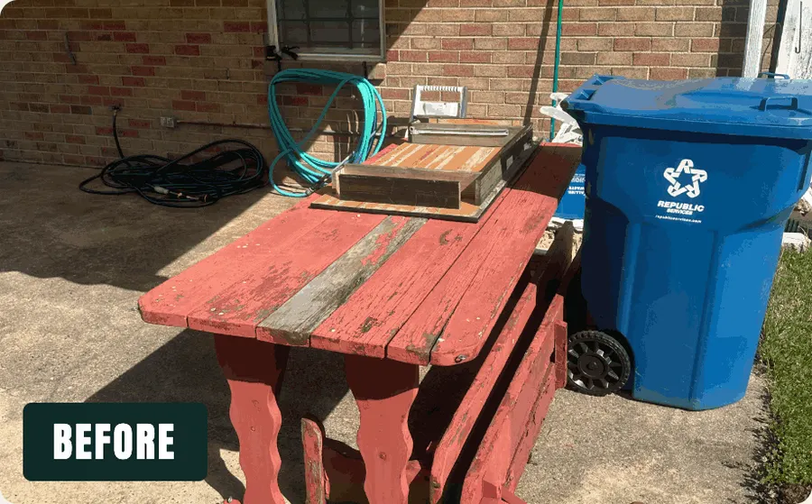 Patio crowded with an old red picnic table and bench